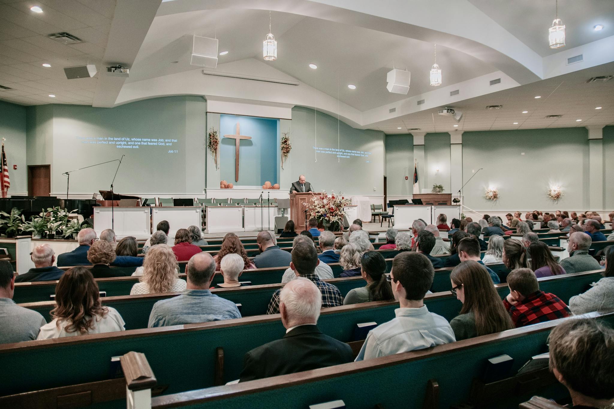 A large congregation listens to a speaker in a modern church setting.